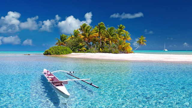polynesia, barca davanti all'isola con le palme